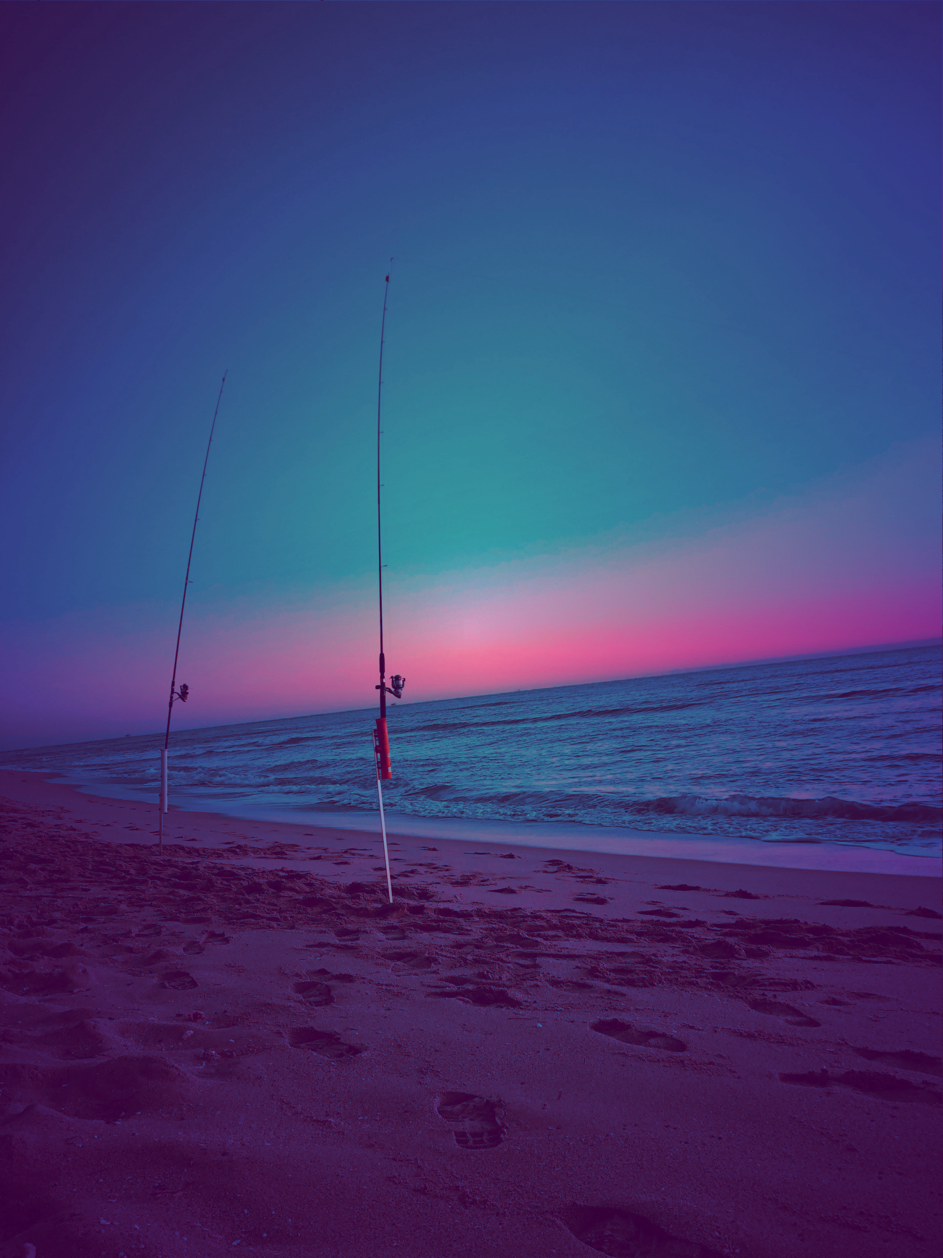 Fishing roads set up on a vacant beach at sunrise.