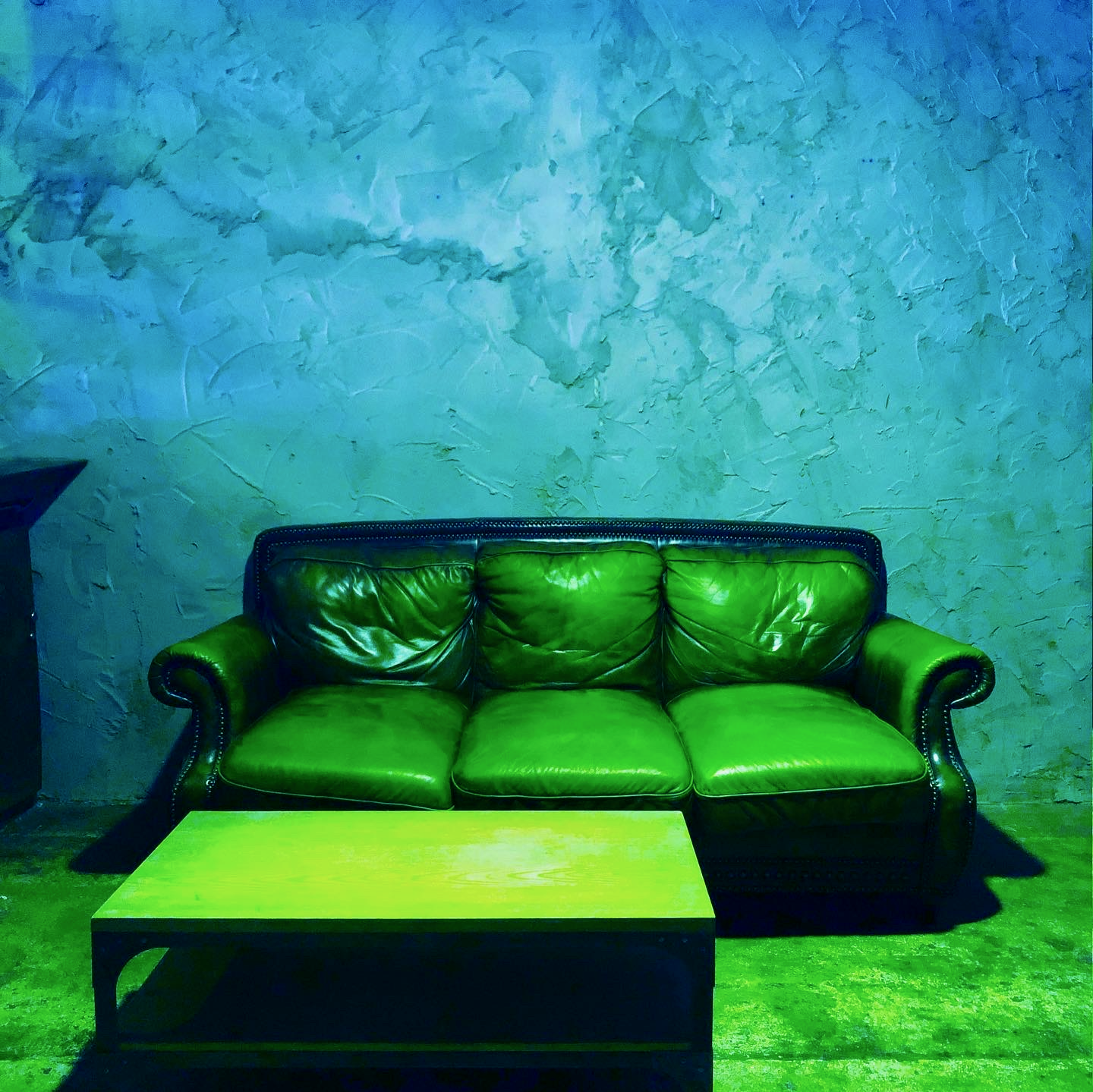 Empty leather sofa and a wooden coffee table. Sci-fi aesthetic with green and yellow colored undertones. 